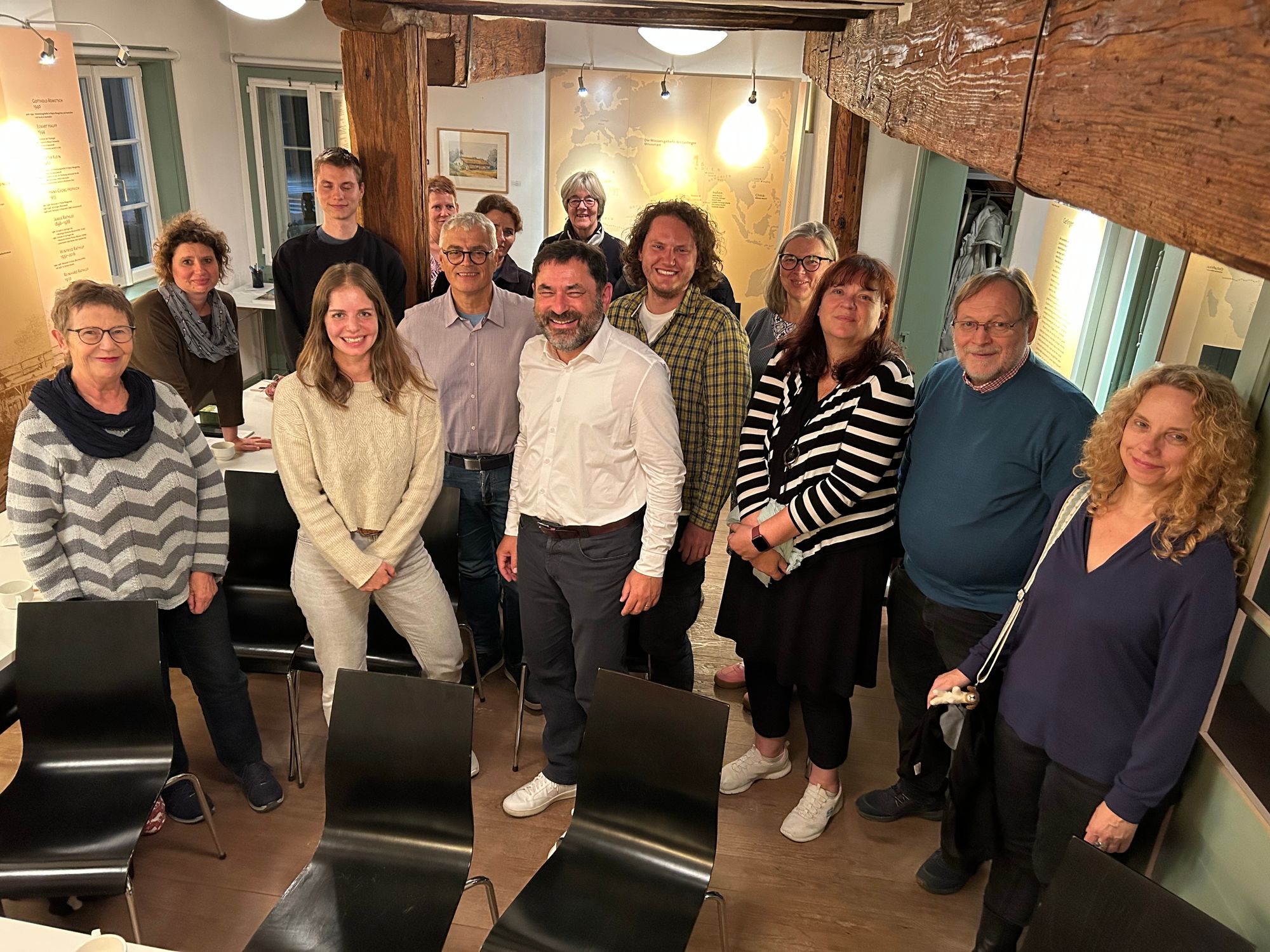 Eine Gruppe von Menschen verschiedenen Alters stehen im Halbkreis und lächeln